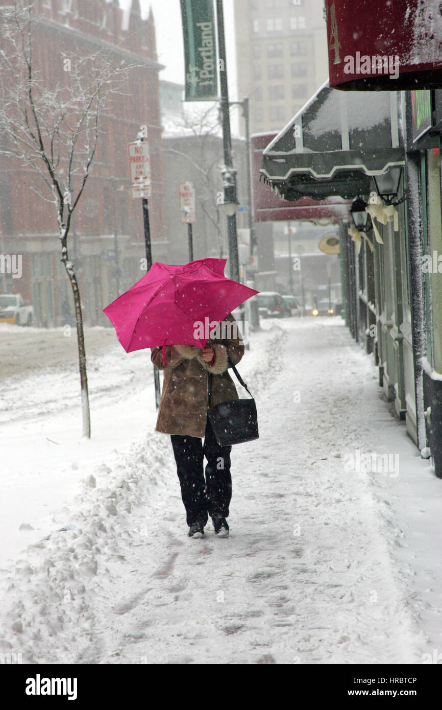 Tempesta di neve Downtown Portland Maine donna camminando sul marciapiede tempesta invernale neve New England USA meteo ghiaccio freddo vento invernale ombrello Foto Stock