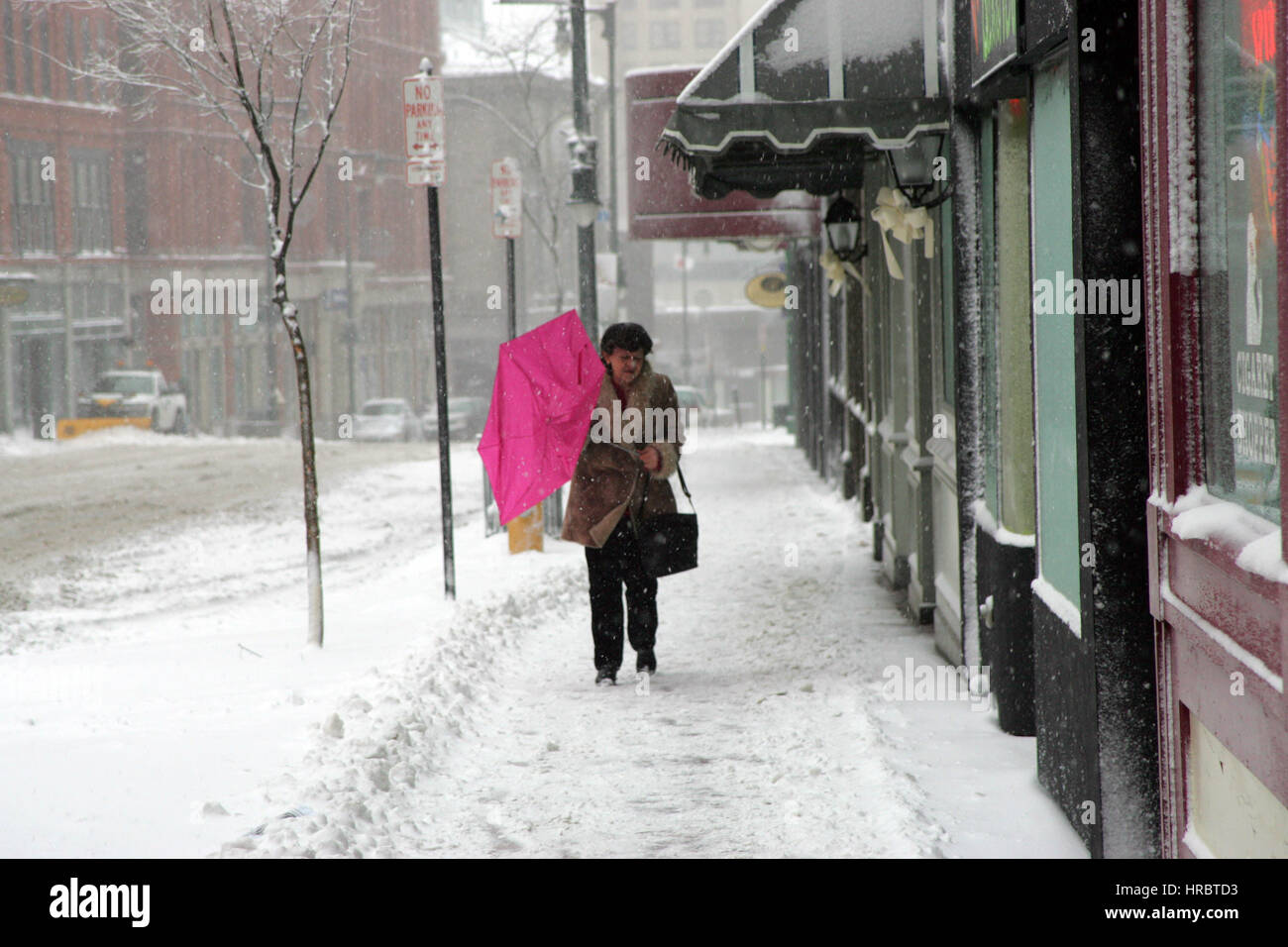 Tempesta di neve Downtown Portland Maine donna camminando sul marciapiede tempesta invernale neve New England USA meteo ghiaccio freddo vento invernale ombrello Foto Stock