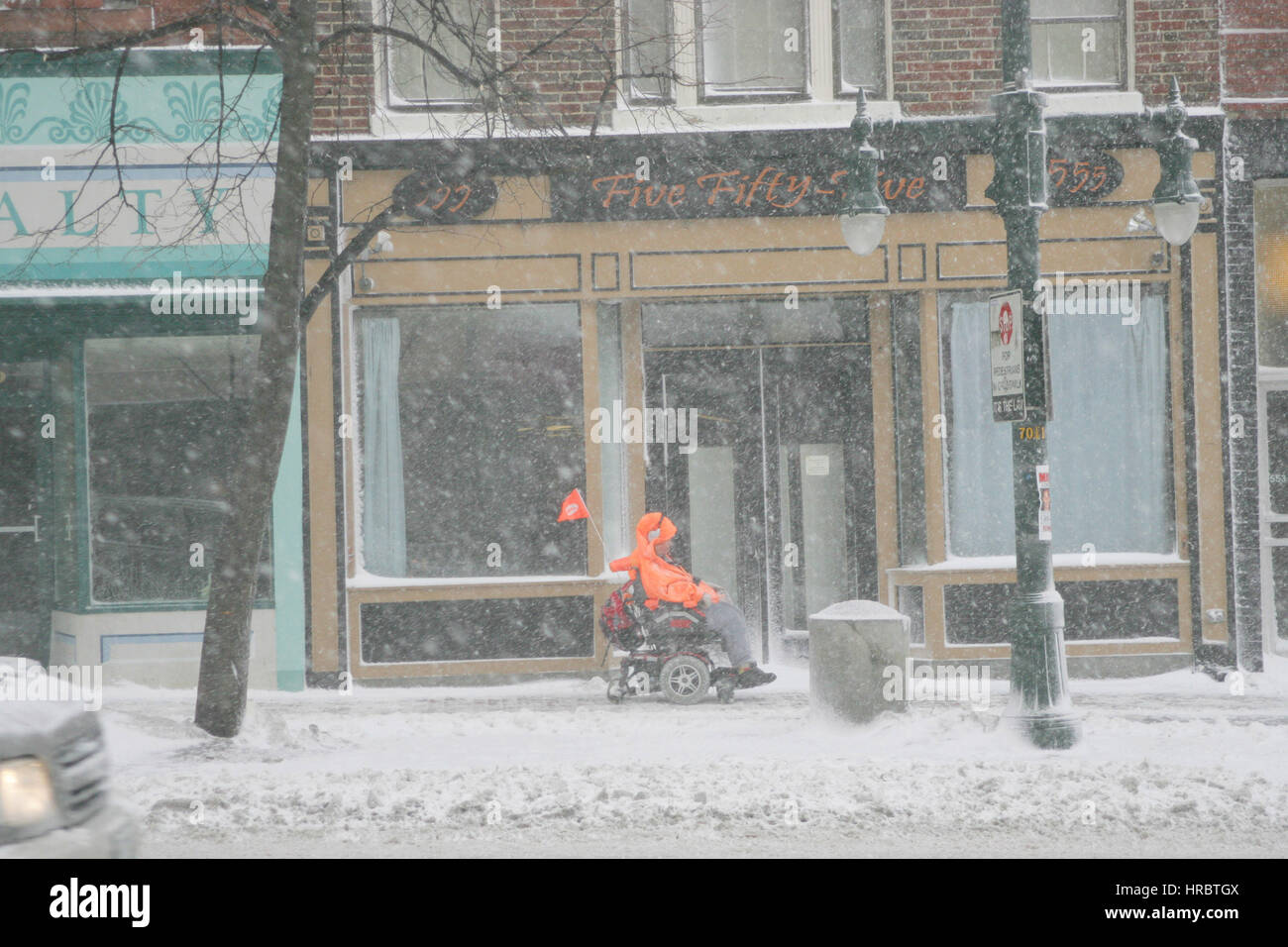 Persona disabile in carrozzella naviga Snowstorm Downtown Portland Maine tempesta di neve snow New England USA meteo ghiaccio freddo inverno Foto Stock