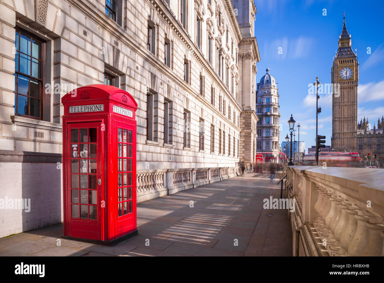Tradizionale in rosso british telefono box con il Big Ben e Double Decker bus in background su un pomeriggio soleggiato con cielo blu e nuvole - Londra, Regno Unito Foto Stock