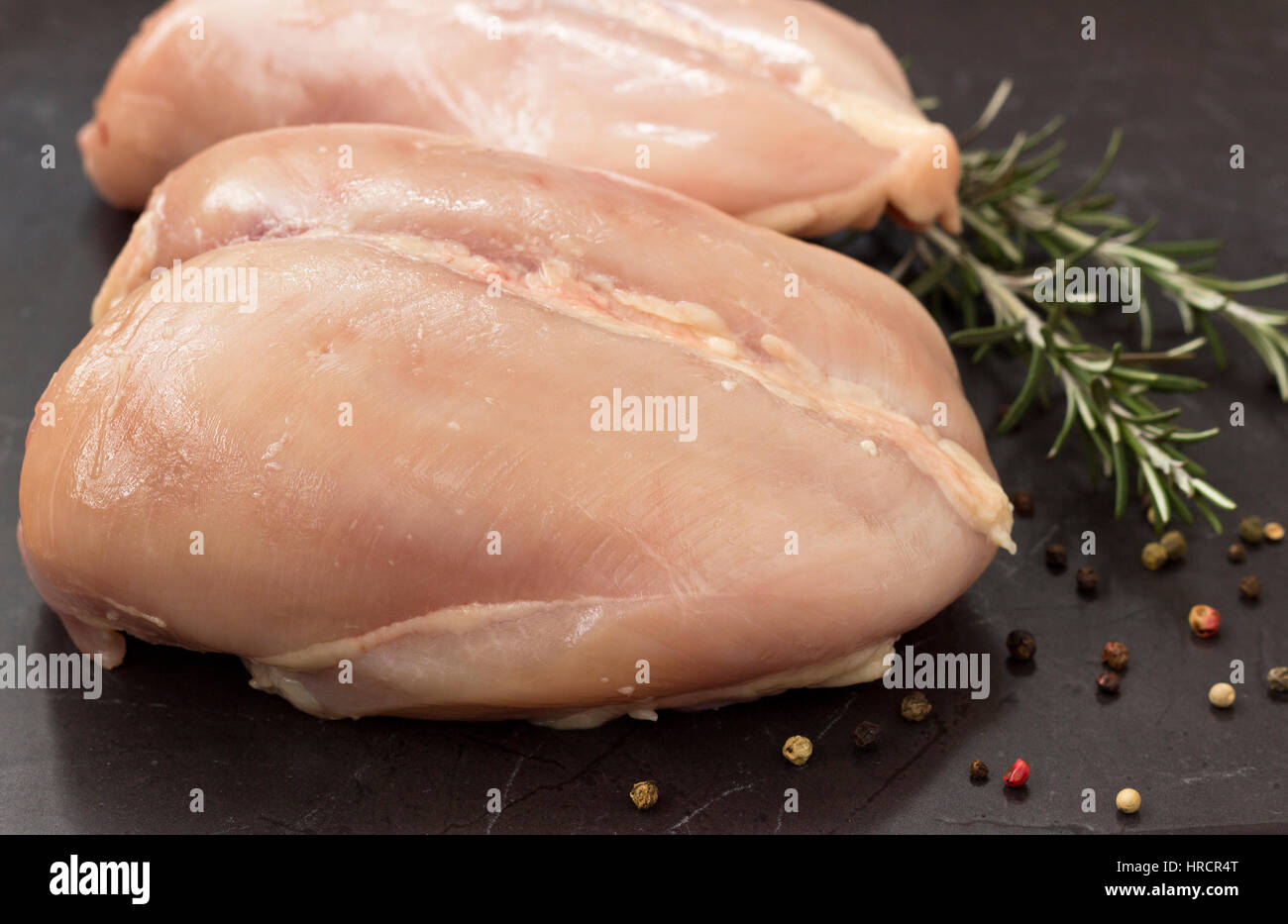 Carni di petto di pollo su nero tavolo di pietra - pronti per la cottura Foto Stock