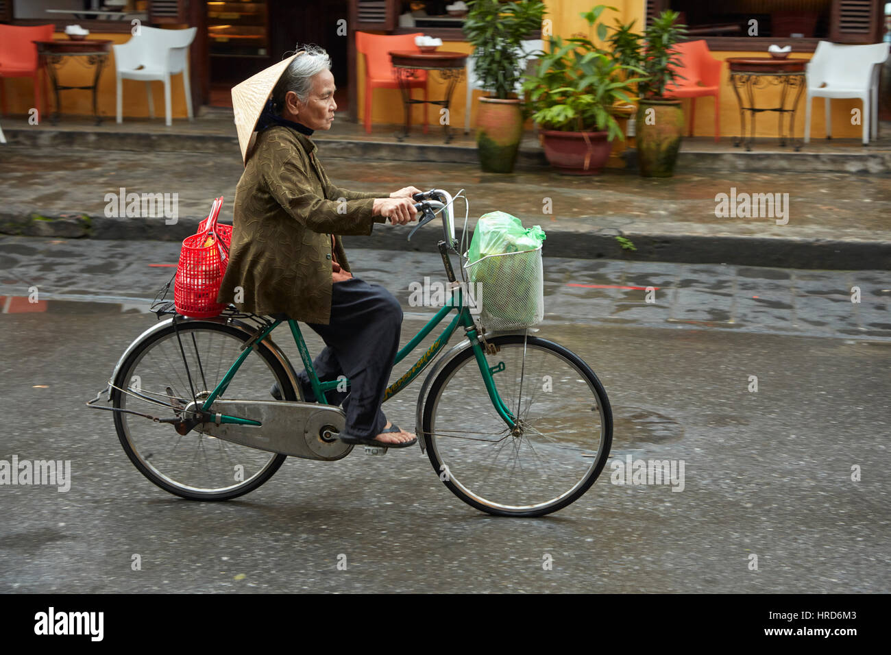 Il vietnamita donna con cappello conico sulla bicicletta, Hoi An (Patrimonio Mondiale dell'UNESCO), Vietnam Foto Stock