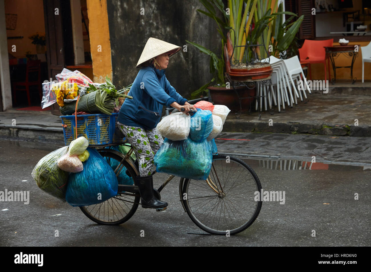 Il vietnamita donna con cappello conico sulla bicicletta, Hoi An (Patrimonio Mondiale dell'UNESCO), Vietnam Foto Stock