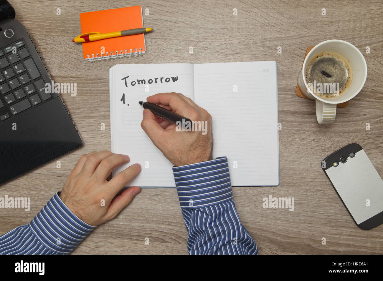 Maschio lato di scrittura di testo ' per fare" in notebook mentre come Lui beve caffè Foto Stock