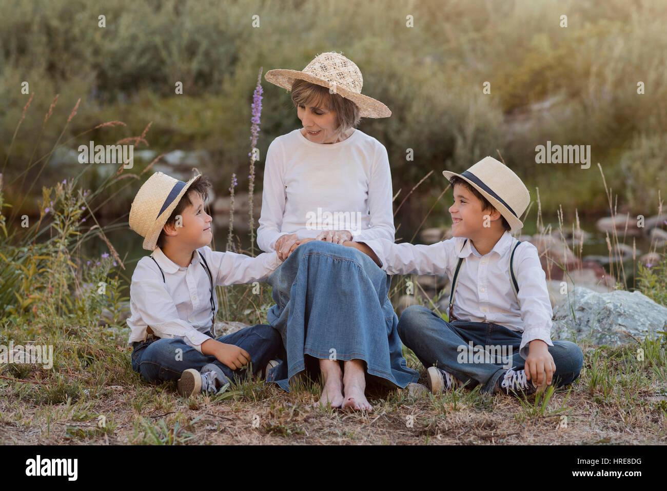 Nonna con i suoi nipoti seduti nel campo Foto Stock