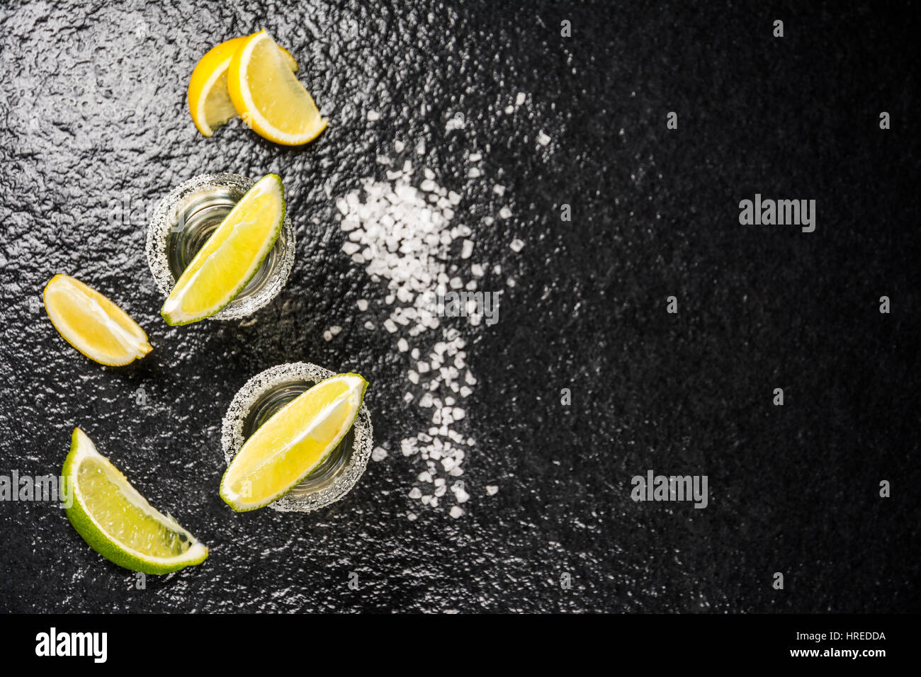 Messicano bevanda alcolica tequila con sale e succo di limone o lime nero sul tavolo in pietra vista superiore Foto Stock