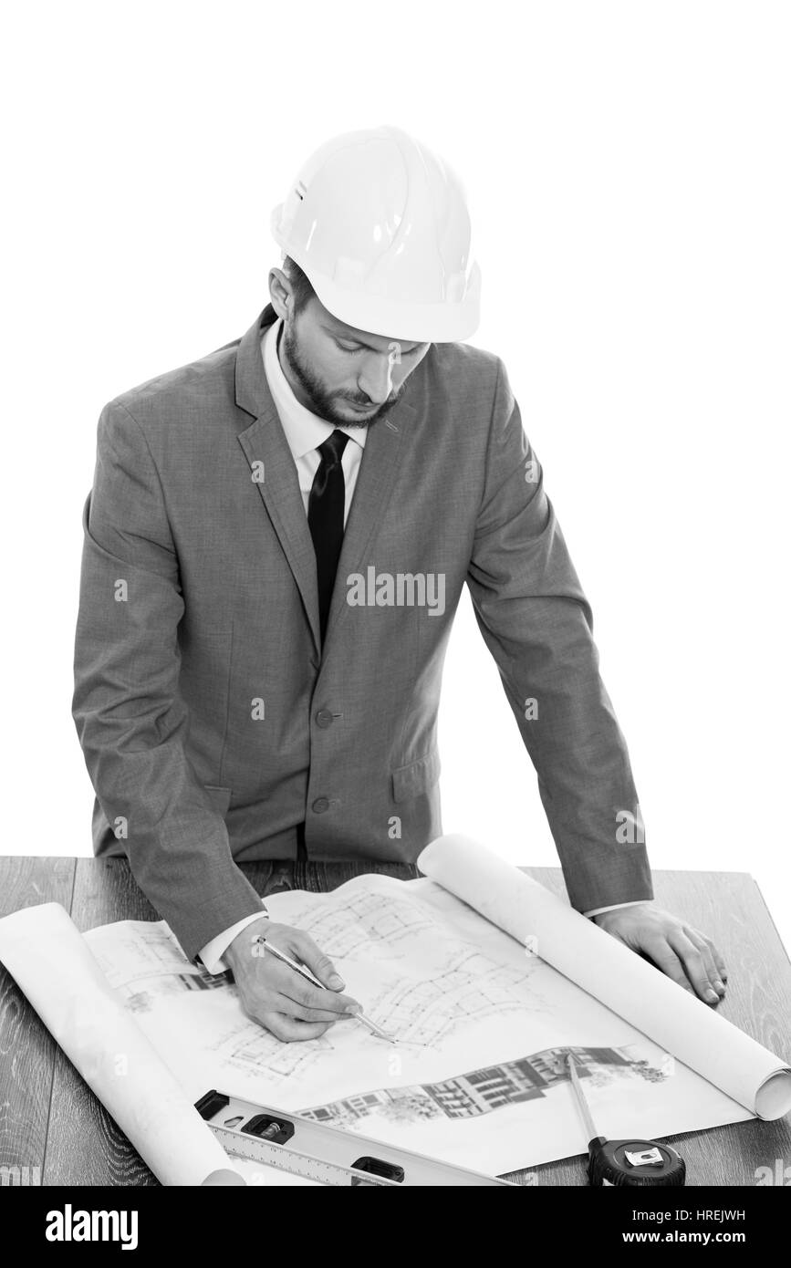 Architetto operante. Bianco e nero ritratto in studio professionali di un ingegnere maschio indossare casco protettivo disegno piani di costruzione architetto lavoratore f Foto Stock