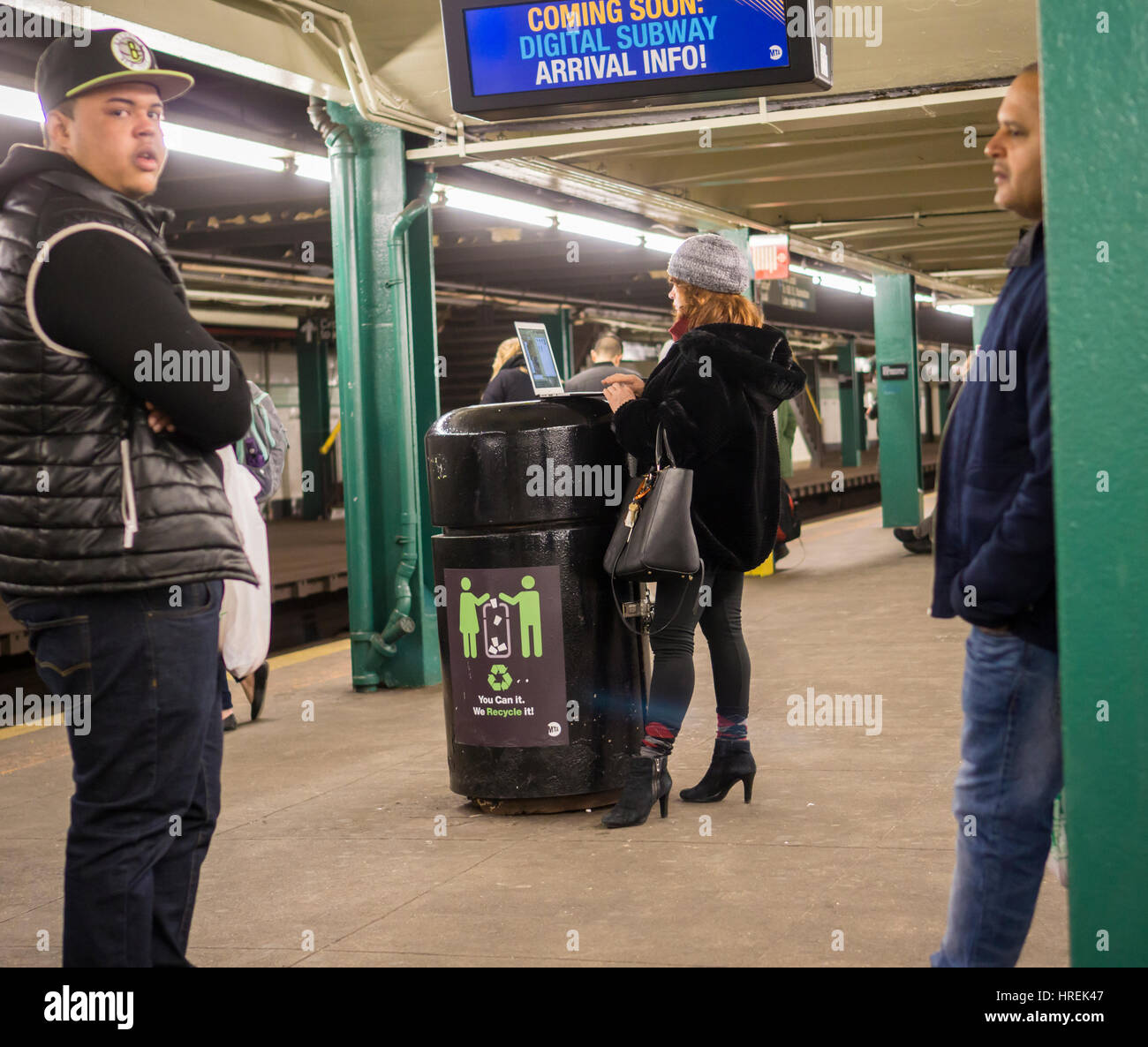 Una donna puntelli il suo computer portatile su un ricettacolo di rifiuti in attesa del treno alla stazione Hoyt-Schermerhorn di Brooklyn a New York martedì, 21 febbraio 2017. (© Richard B. Levine) Foto Stock