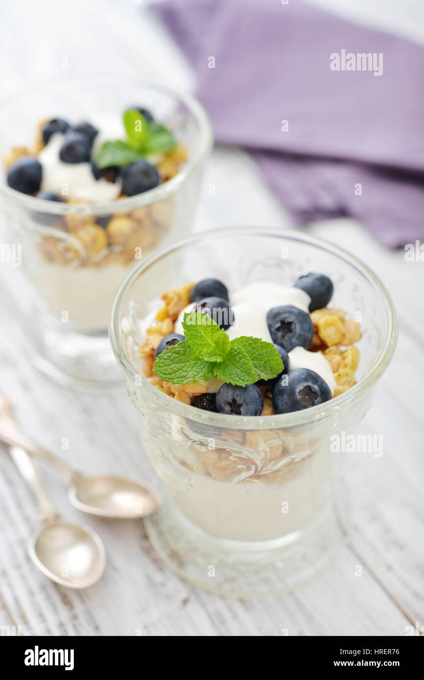 Muesli con yogurt e mirtillo in vetro su sfondo di legno Foto Stock
