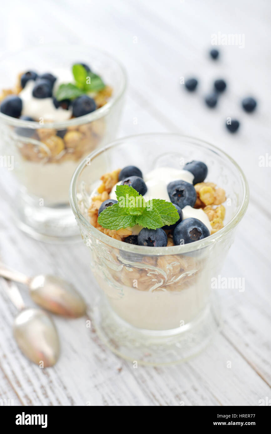 Muesli con yogurt e mirtillo in vetro su sfondo di legno Foto Stock