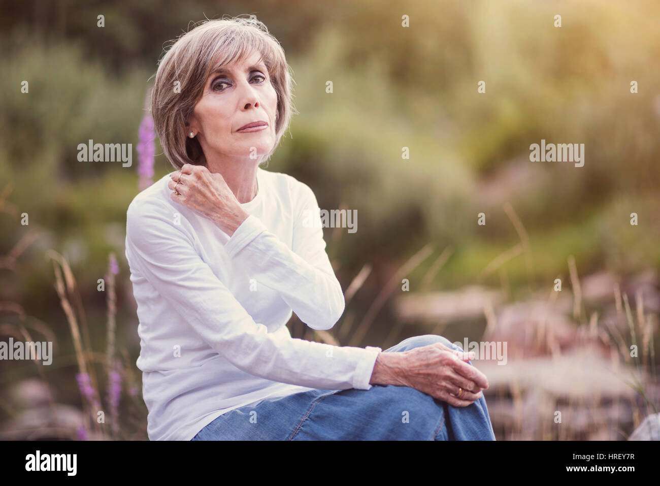 Felice senior donna seduta sull'erba Foto Stock