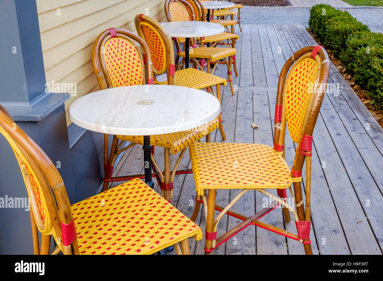 Arancio brillante e di colore rosso in vimini di plastica Sedie bistrot circondano tavolo bianco al di fuori di un coffee shop in Niagara sul lago, Canada. Foto Stock