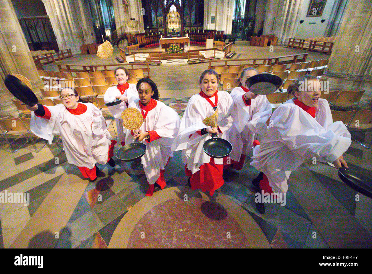 Il ragazzo e una ragazza coristi praticando il lunedì mattina (Feb 27) a Ely Cathedral in Cambridgeshire di domani Martedì Grasso pancake race svoltosi nella Cattedrale. Coristi sono stati la pratica per il pancake tradizionale gara a Ely Cathedral in Cambridgeshire Domani (martedì). Il resident coristi indossavano i loro il bianco e il rosso cassocks come esse ribaltate frittelle a mark Martedì Grasso. I ragazzi e le ragazze ha trascorso circa un' ora di perfezionare la loro pancake tossing competenze per l'evento annuale. Ogni anno circa 20 coristi gara giù la navata della cattedrale del XII secolo dopo Evensong. Foto Stock