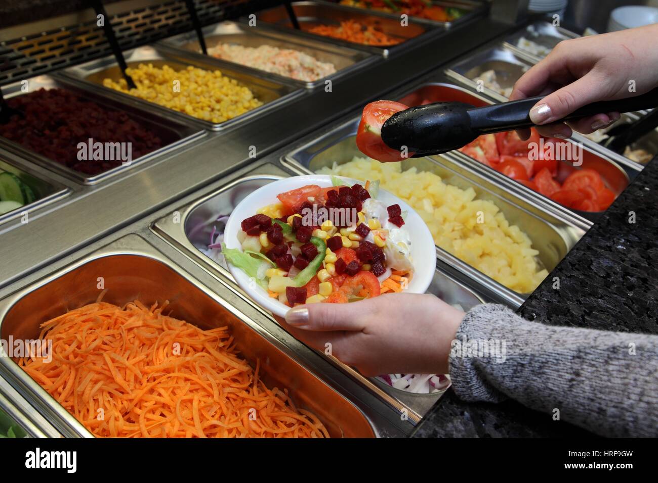 Qualcuno il caricamento di una lastra al salad bar di un Harvester pub bar ristorante Foto Stock