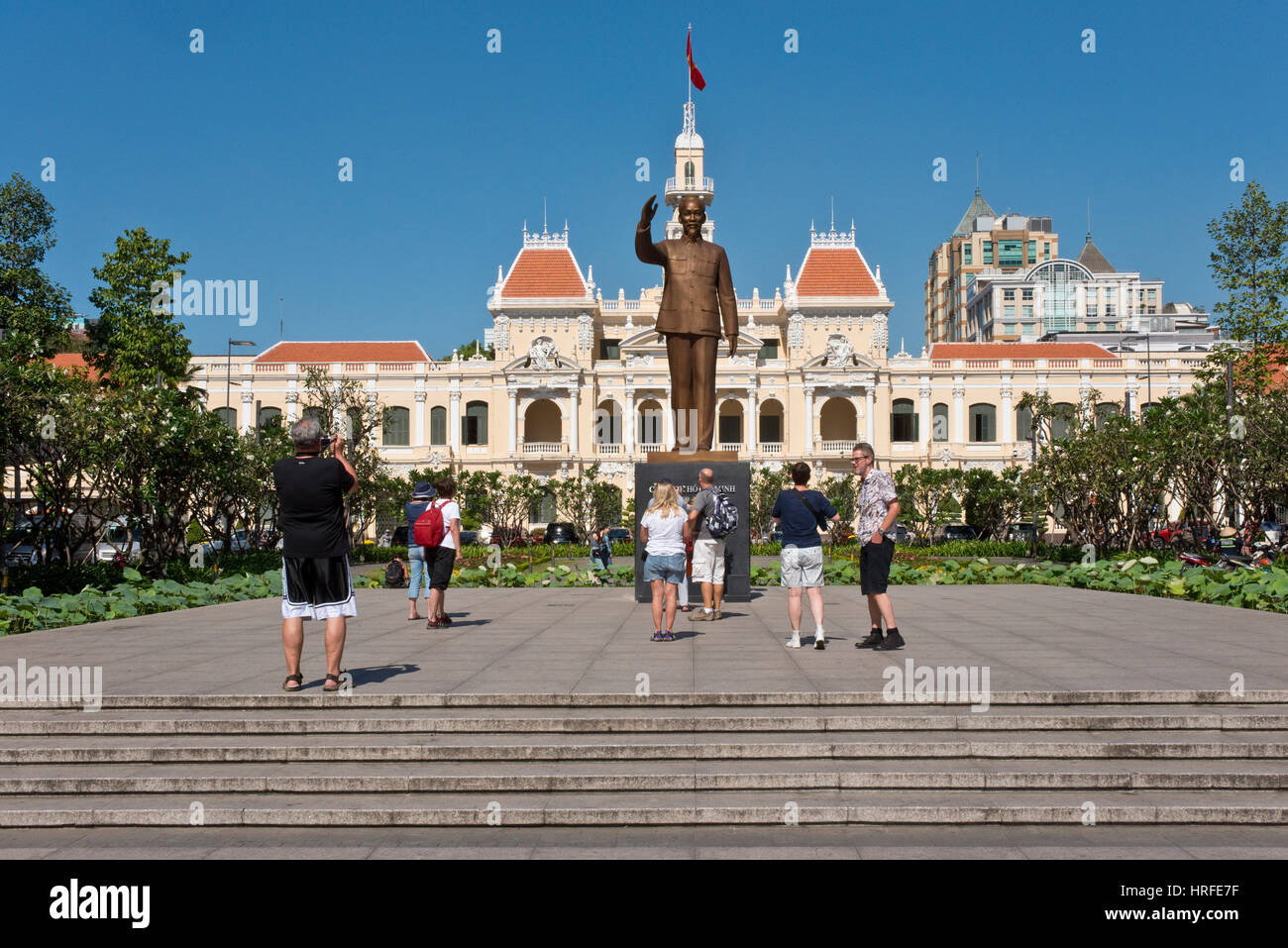La statua in bronzo di Ho Chi Minh che sorge al di fuori della città di Ho Chi Minh Hall in una giornata di sole con cielo blu e turisti fotografare. Foto Stock