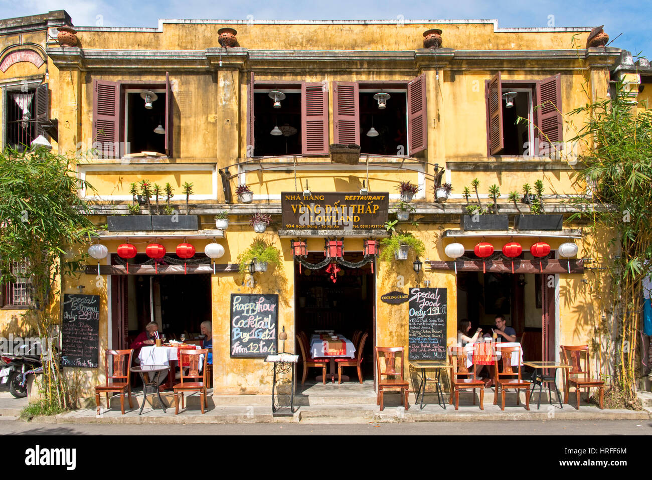 Una scena di strada in Hoi An old town con i turisti in un ristorante o bar che mostra tipica architettura coloniale. Foto Stock