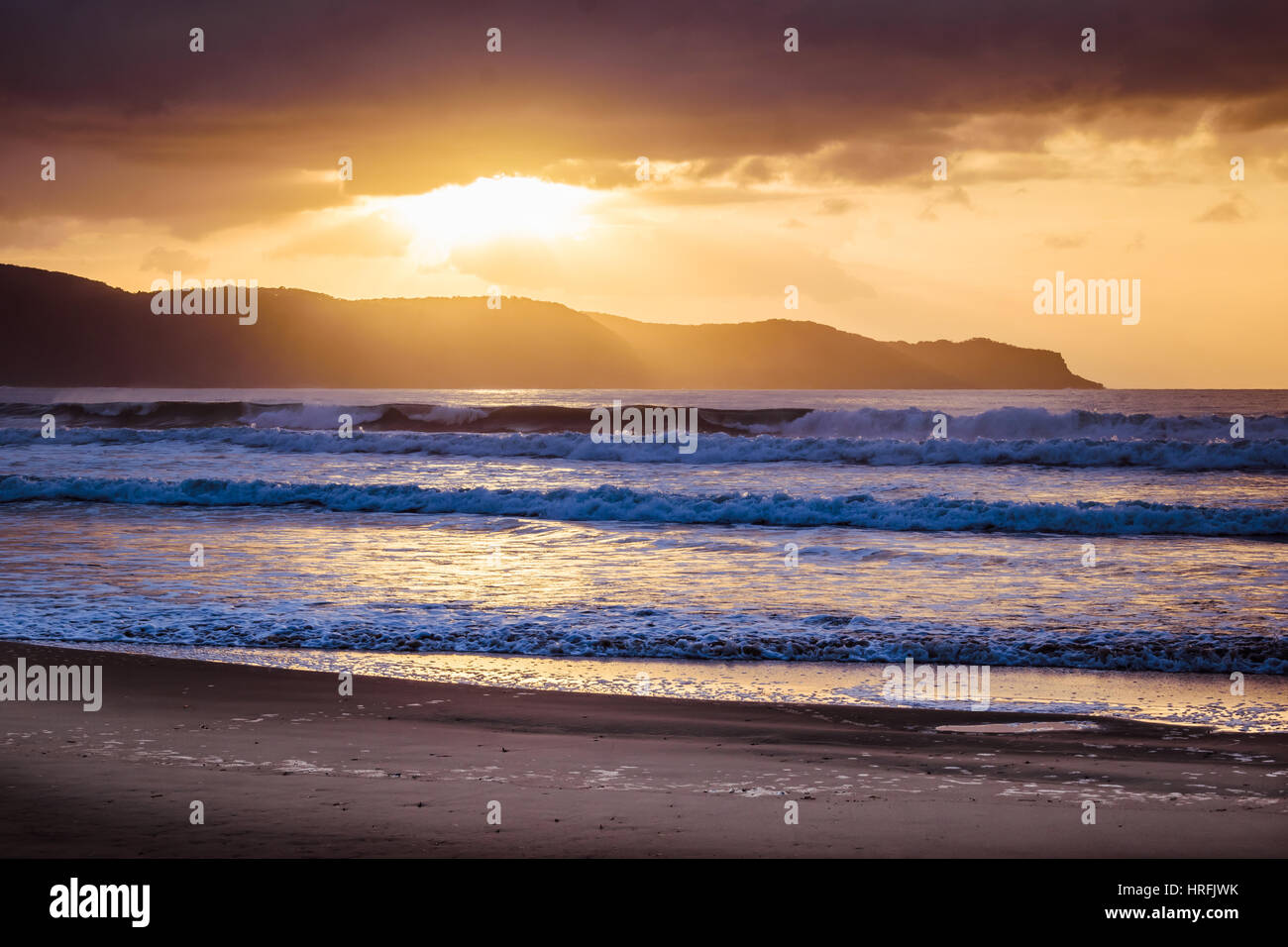 Sunrise seascape con sfondo di montagne, Australia Foto Stock