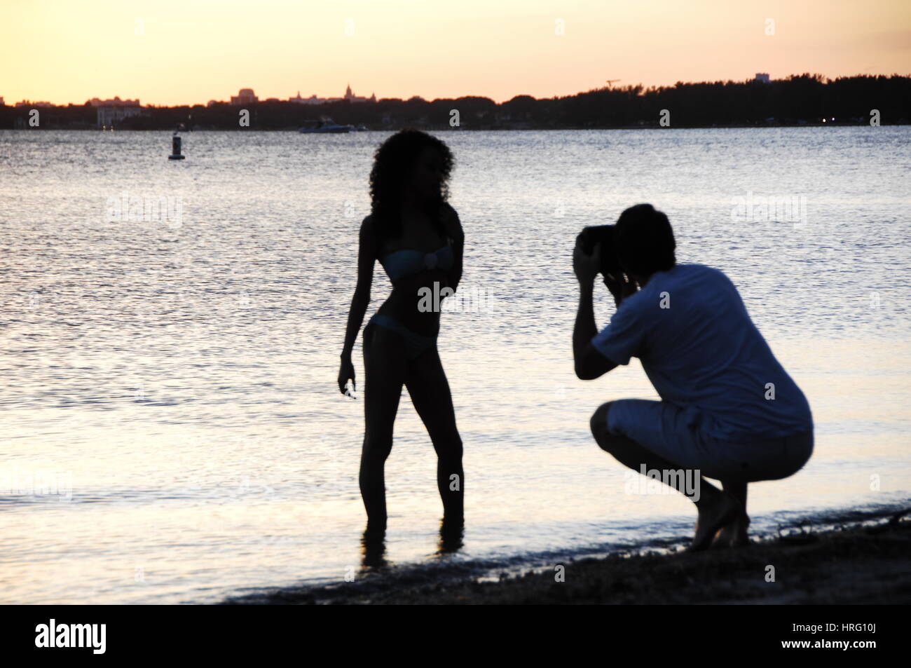 Fotografo prende le immagini di un modello al tramonto sul mare lo skyline di Miami al tramonto, da Key Biscayne Foto Stock