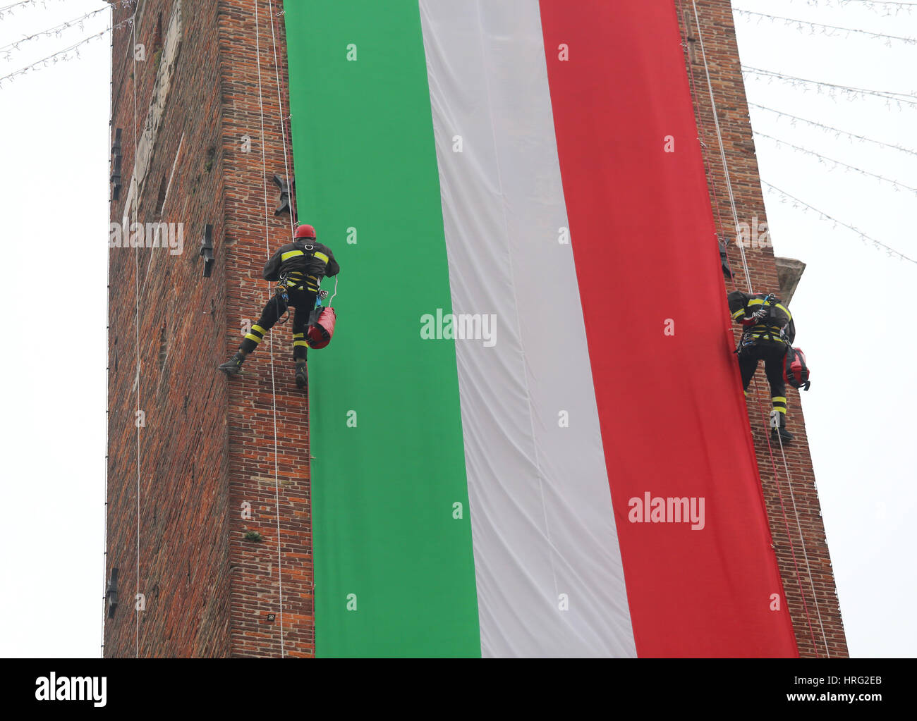 Italiano intrepidi coraggiosi vigili del fuoco salire la vecchia torre con un gigante bandiera italiana Foto Stock