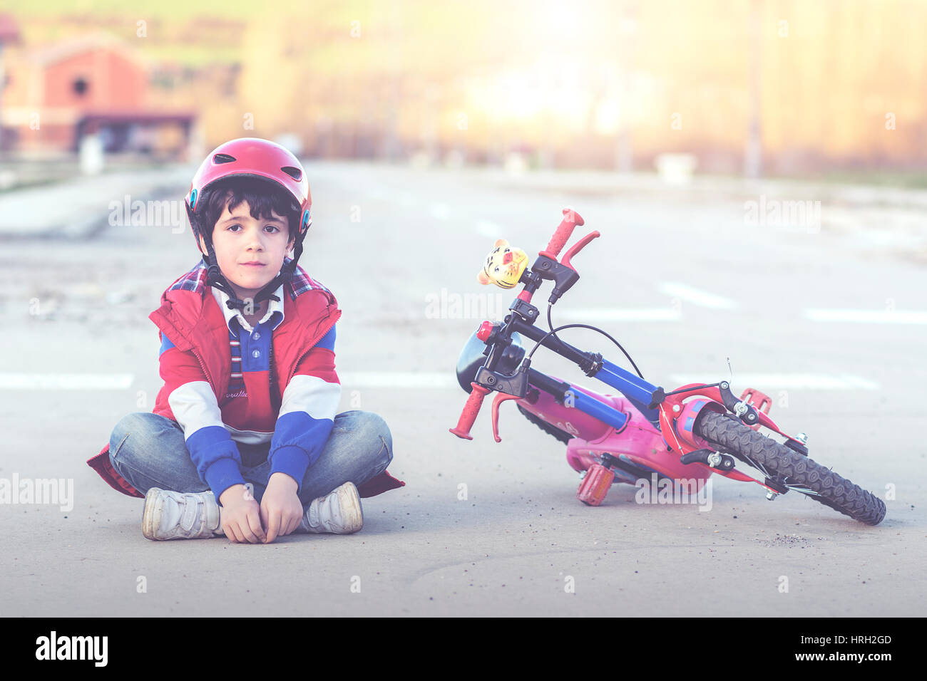 Ragazzo con una bicicletta seduti sulla strada Foto Stock