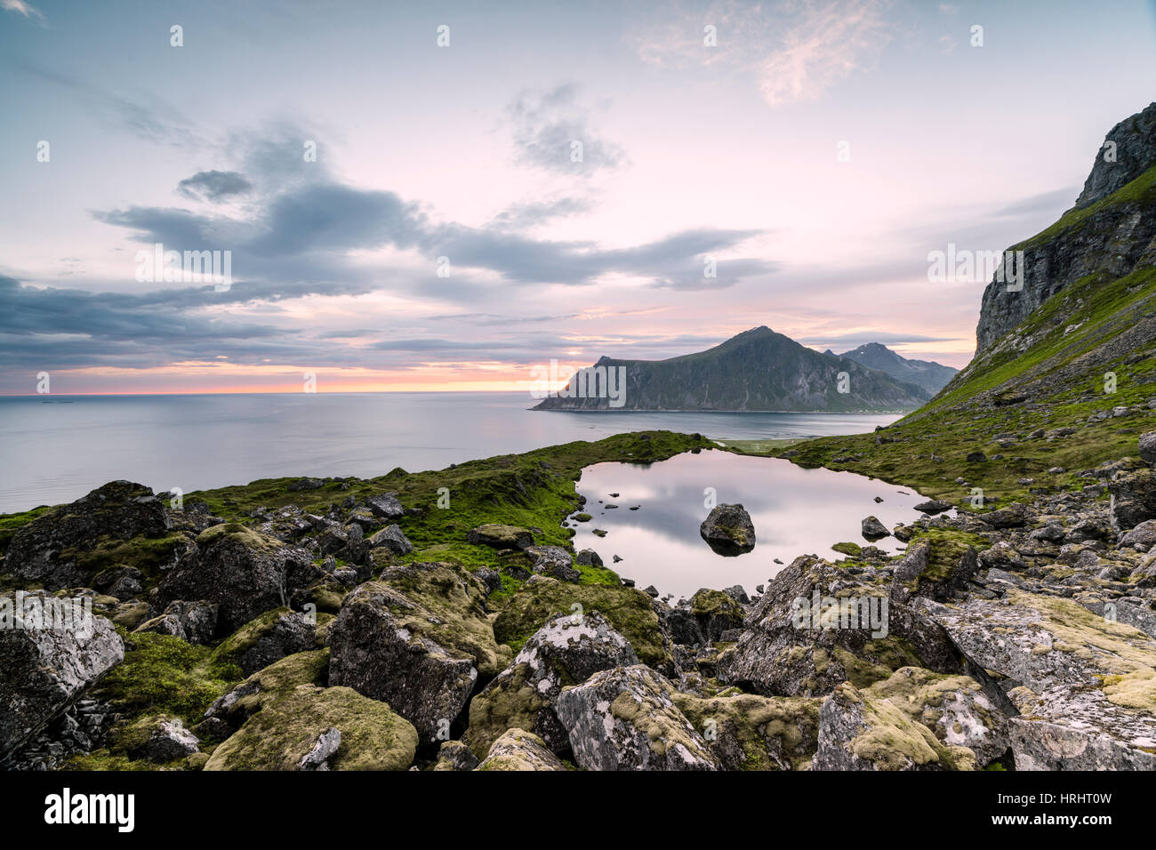 Nuvole rosa del sole di mezzanotte si riflette nel mare freddo, Flakstad, Moskenesoya, Nordland county, Isole Lofoten in Norvegia Foto Stock