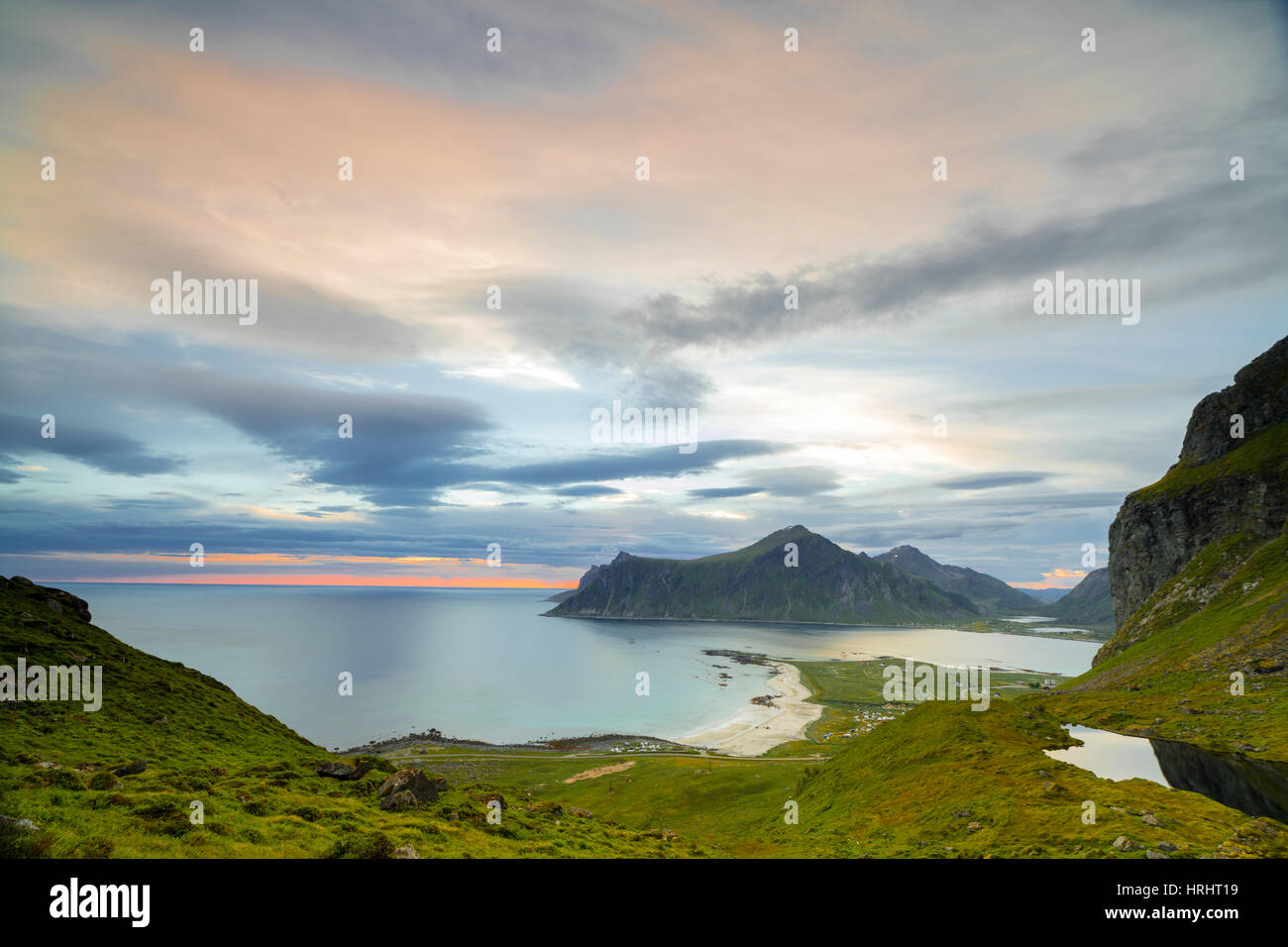 Nuvole rosa del sole di mezzanotte si riflette nel mare freddo, Flakstad, Moskenesoya, Nordland county, Isole Lofoten in Norvegia Foto Stock