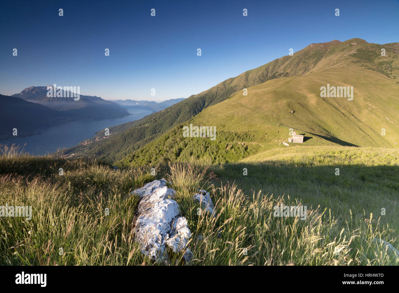 Sunbeam sulla chiesa di San Bernardo si illumina il paesaggio attorno alle acque blu del lago di Como a Alba, Musso, Lombardia, Italia Foto Stock