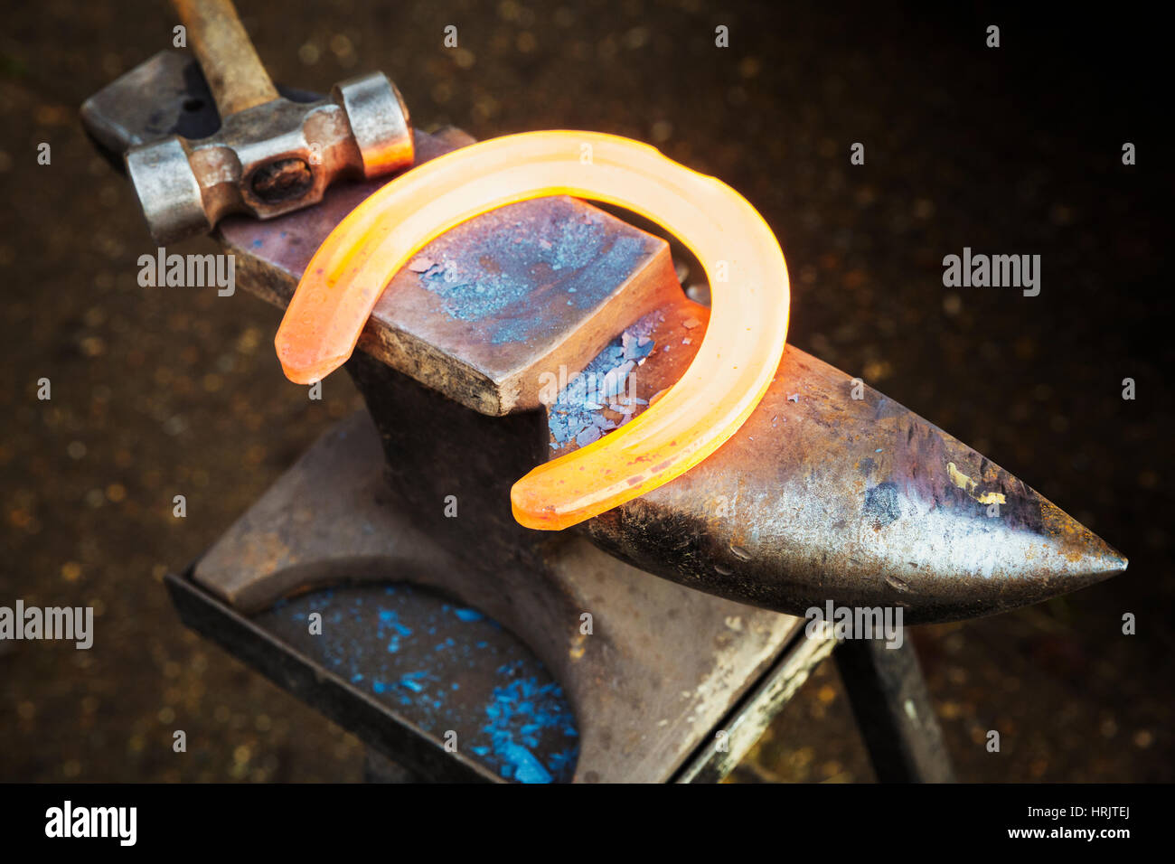 Un rosso incandescente metallo riscaldato il ferro di cavallo e un martello su un'incudine. Fabbro attrezzature. Foto Stock