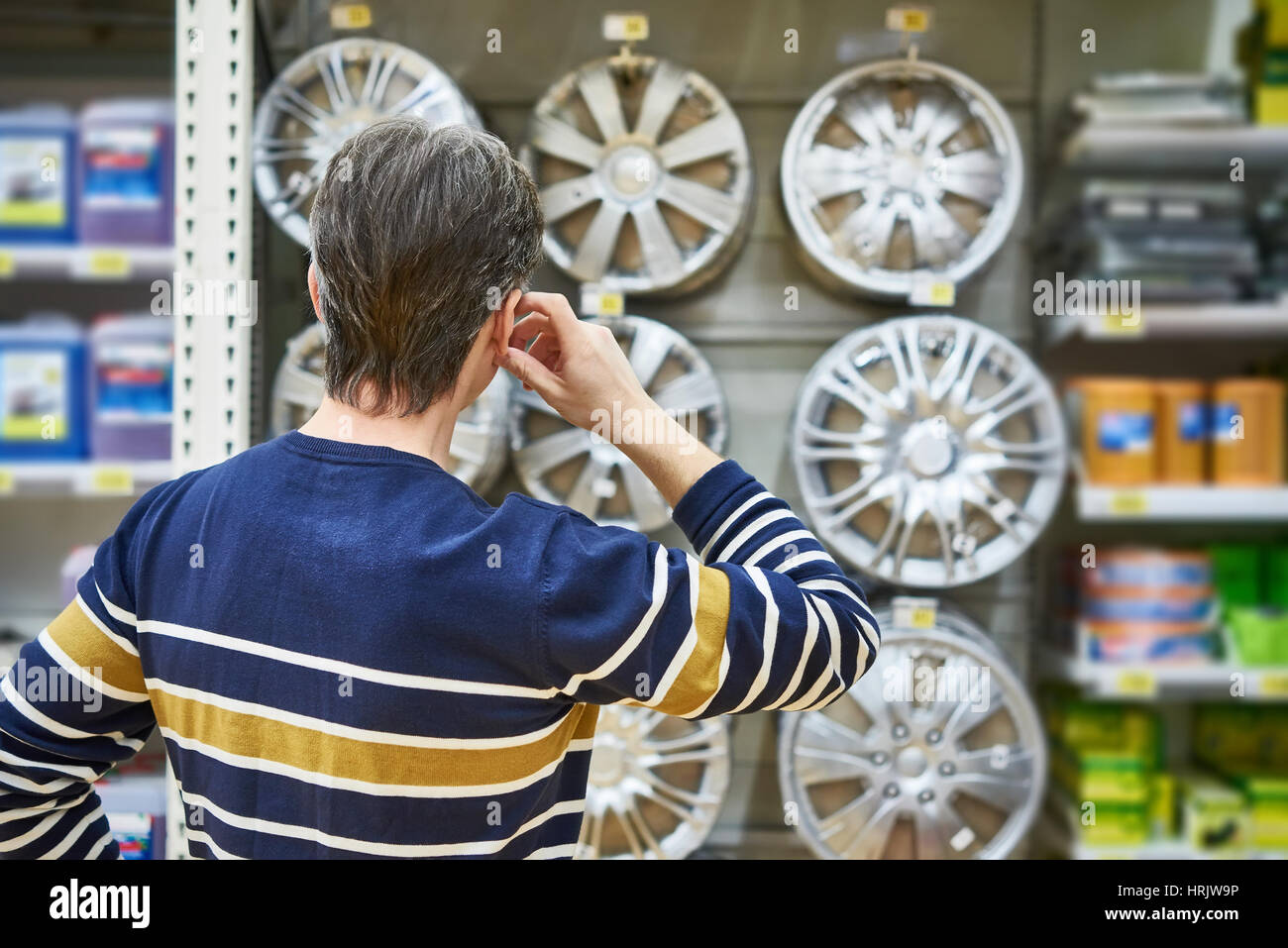 Uomo sceglie i cerchi in lega per la tua auto le ruote nel supermercato Foto Stock
