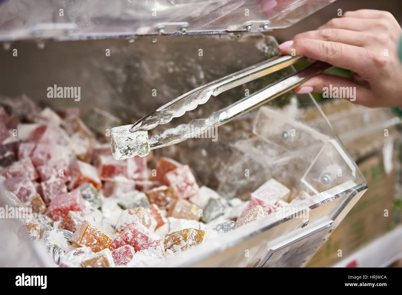 Acquirente in negozio acquista turkish delight servendosi di un paio di pinze per i prodotti Foto Stock