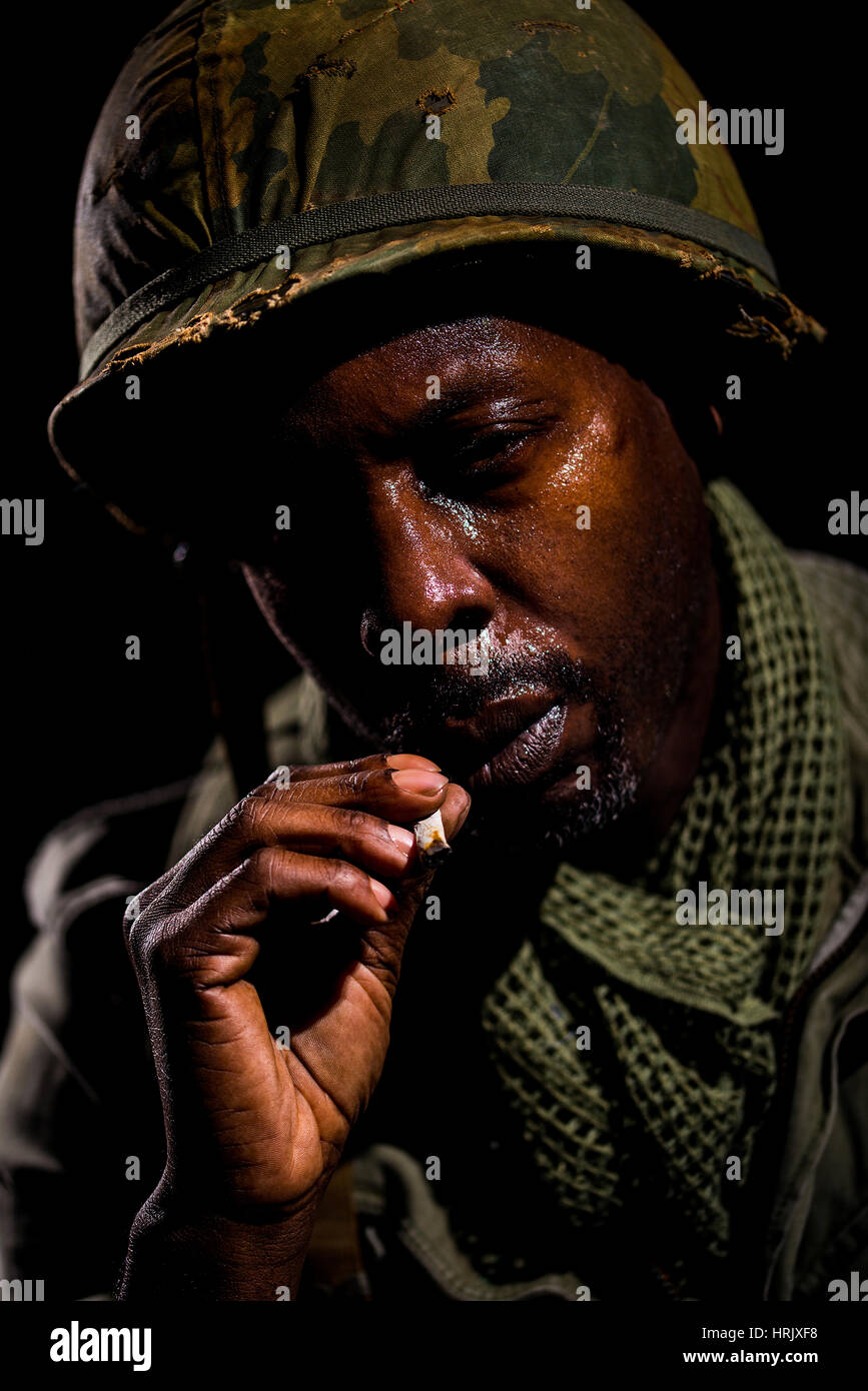 Ritratto di soldato afro-americana dalla guerra del Vietnam periodo contro uno sfondo nero. Ombre scure utilizzati per una più drammatica immagine. Foto Stock