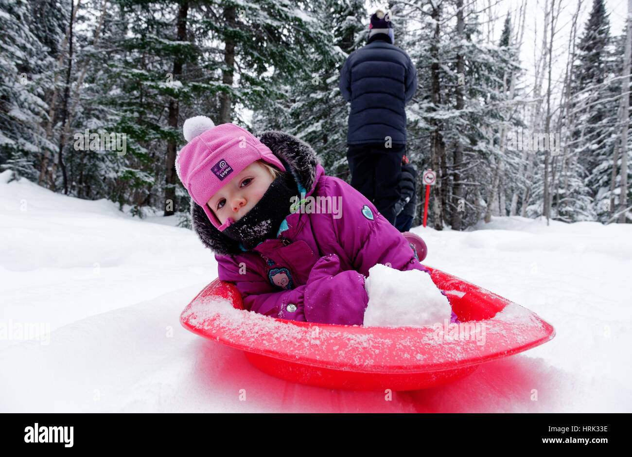 Una bambina di 2 anni che viene tirata da sua madre in una slitta Foto Stock