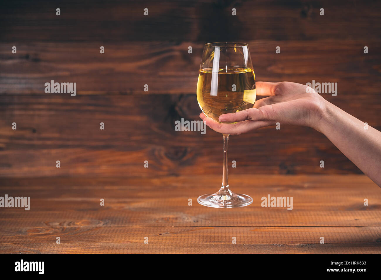 Donna mano tifo con bicchieri di vino bianco contro lo sfondo di legno Foto Stock