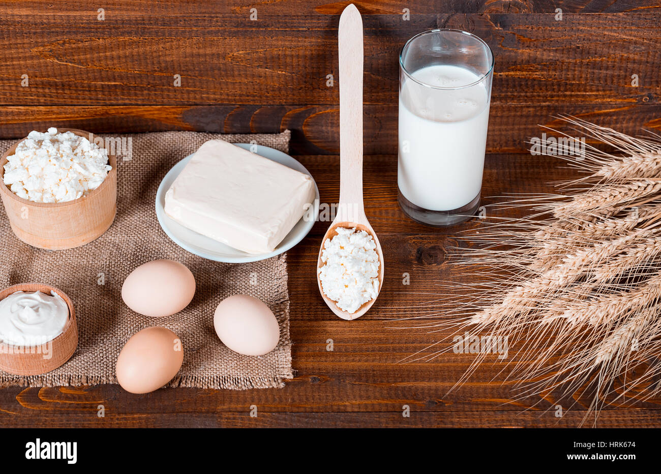 Naturale prodotti fatti in casa: latte, formaggio, panna acida e uova sul vecchio sfondo di legno con spighe di grano. Con spazio per il testo Foto Stock