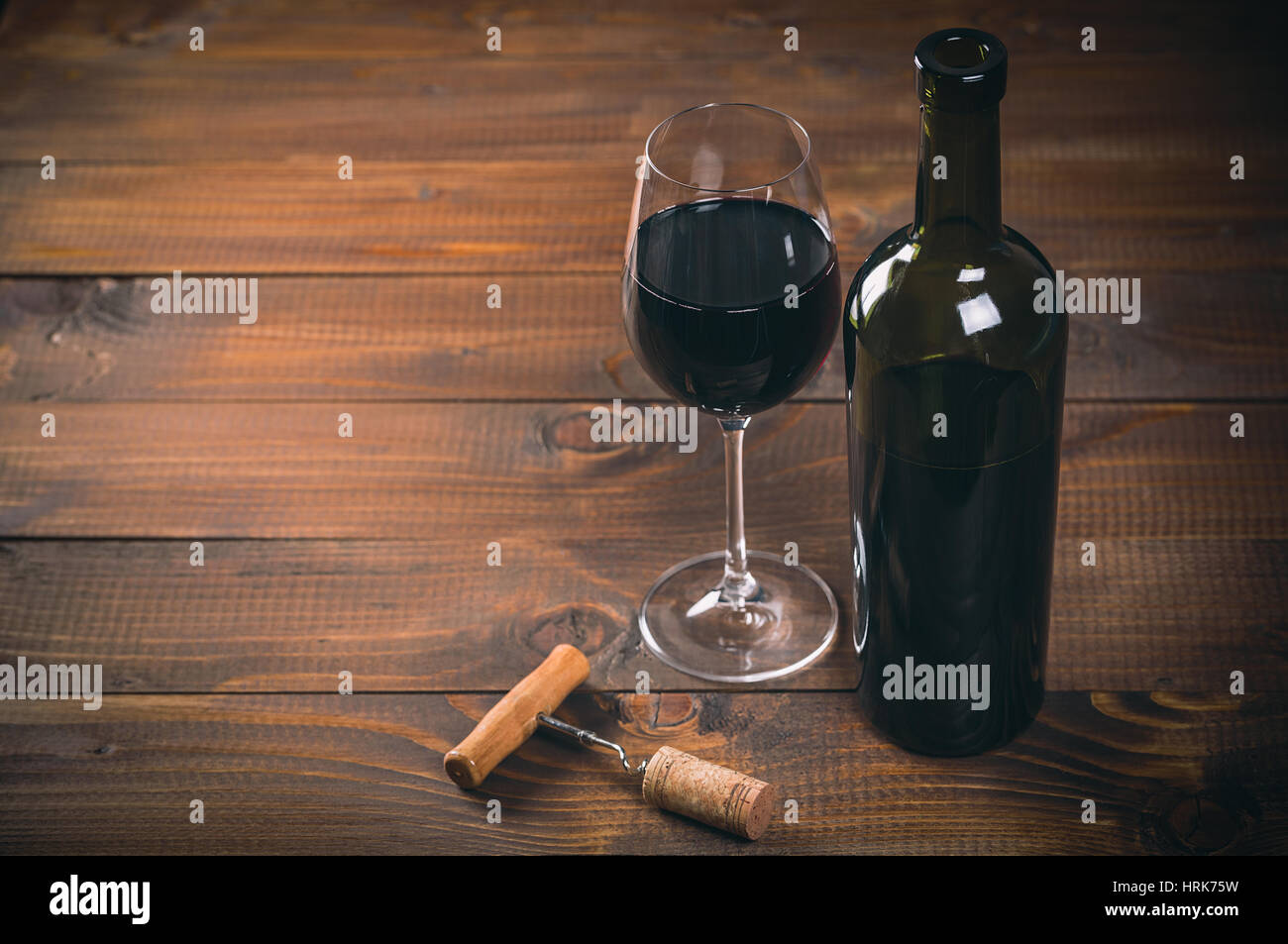 Bottiglia di vino rosso e vetro, cavatappi e tappi sul tavolo di legno Foto Stock