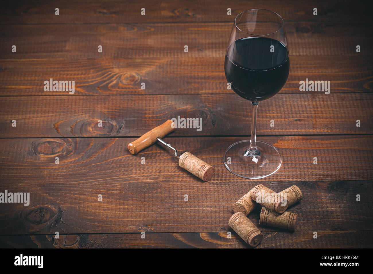 Bicchiere di vino rosso, cavatappi e tappi sul tavolo di legno Foto Stock