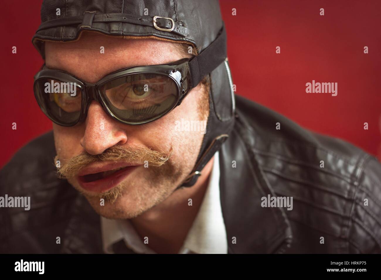 Uomo che indossa aviatore cappello e occhiali rende stupida espressione  facciale dal forte vento Foto stock - Alamy