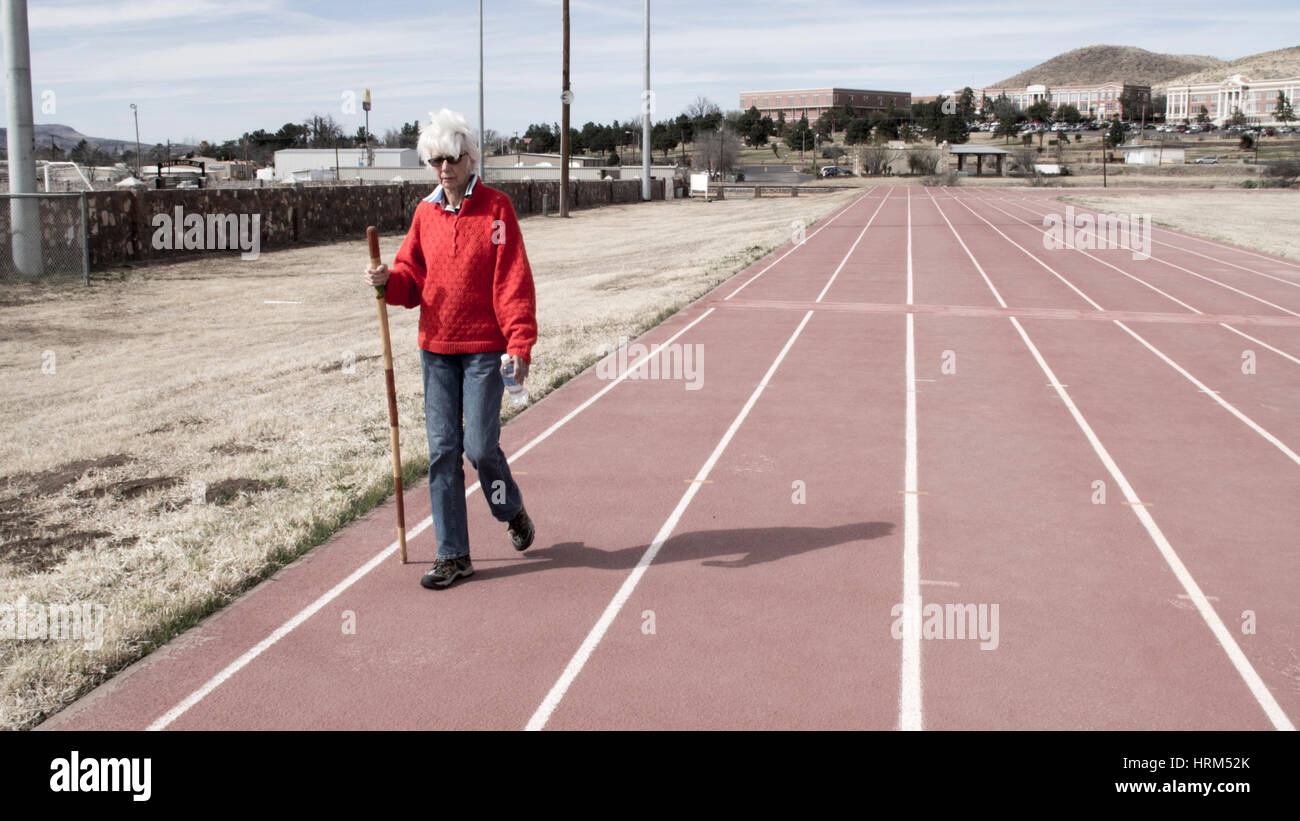Donna anziana a camminare su una pista e field stadium Foto Stock