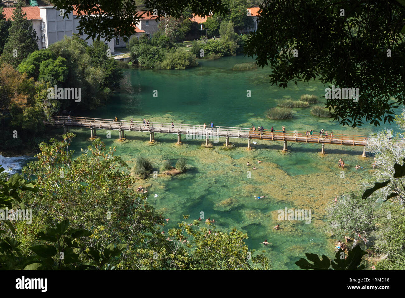 La gente a piedi di un marciapiede elevato e nuotare in un lago presso il Parco Nazionale di Krka in Croazia in una giornata di sole, visto dall'alto. Foto Stock