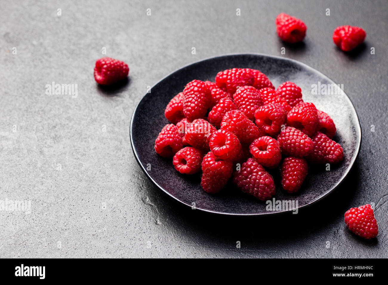 Lamponi freschi su una ciotola nero ardesia sfondo. Foto Stock