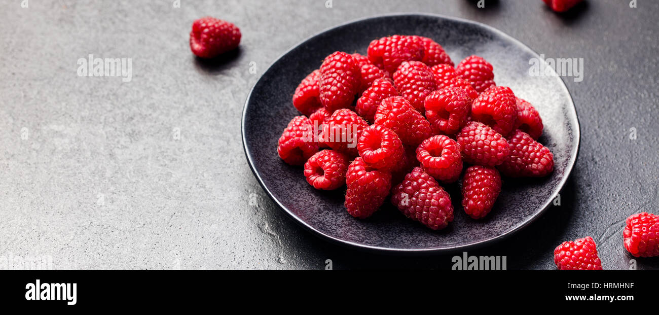 Lamponi freschi su una ciotola nero ardesia sfondo. Foto Stock