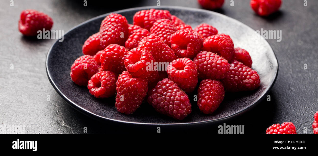 Lamponi freschi su una ciotola nero ardesia sfondo. Foto Stock