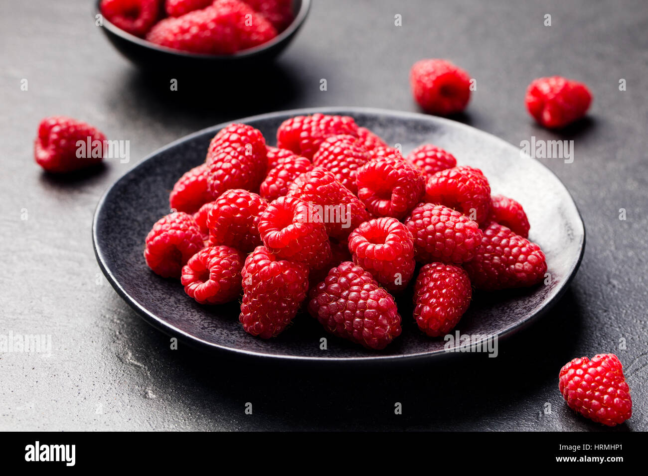 Lamponi freschi su una ciotola nero ardesia sfondo. Foto Stock