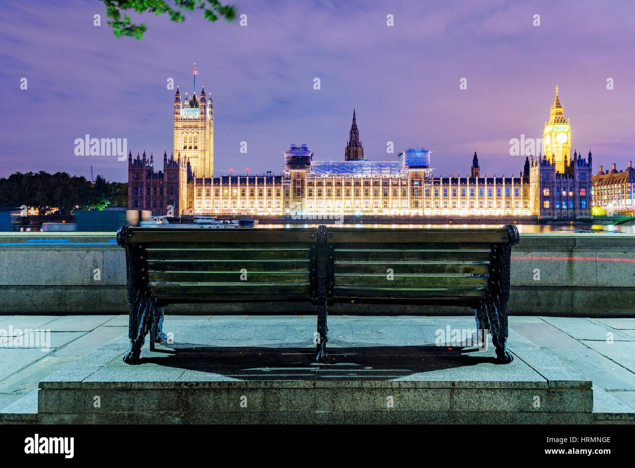Banco a notte con le case del Parlamento a distanza Foto Stock