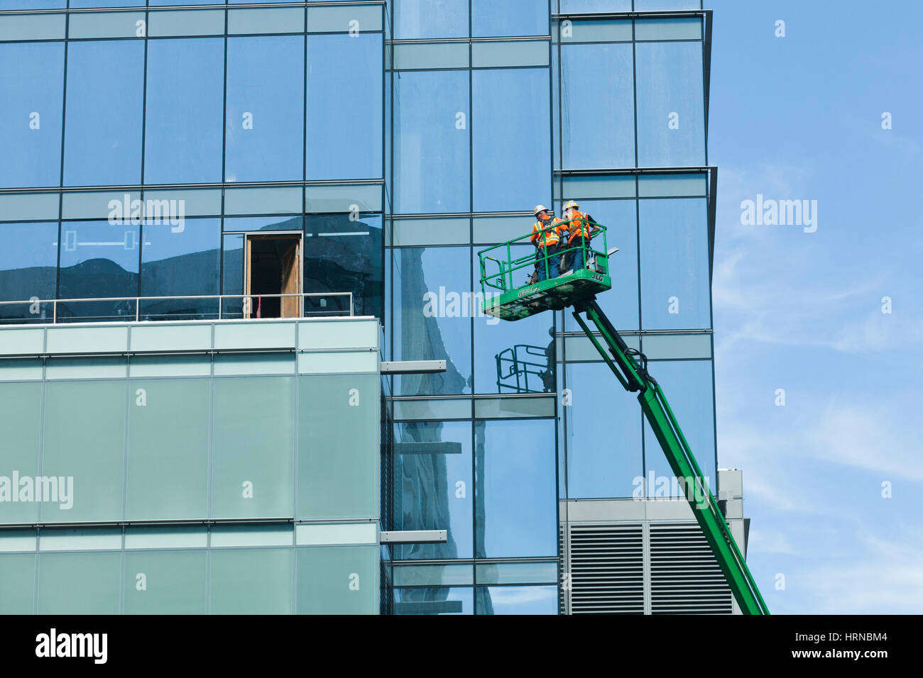 Uomini al lavoro su esterno dell'edificio in cima a un braccio di sollevamento - USA Foto Stock