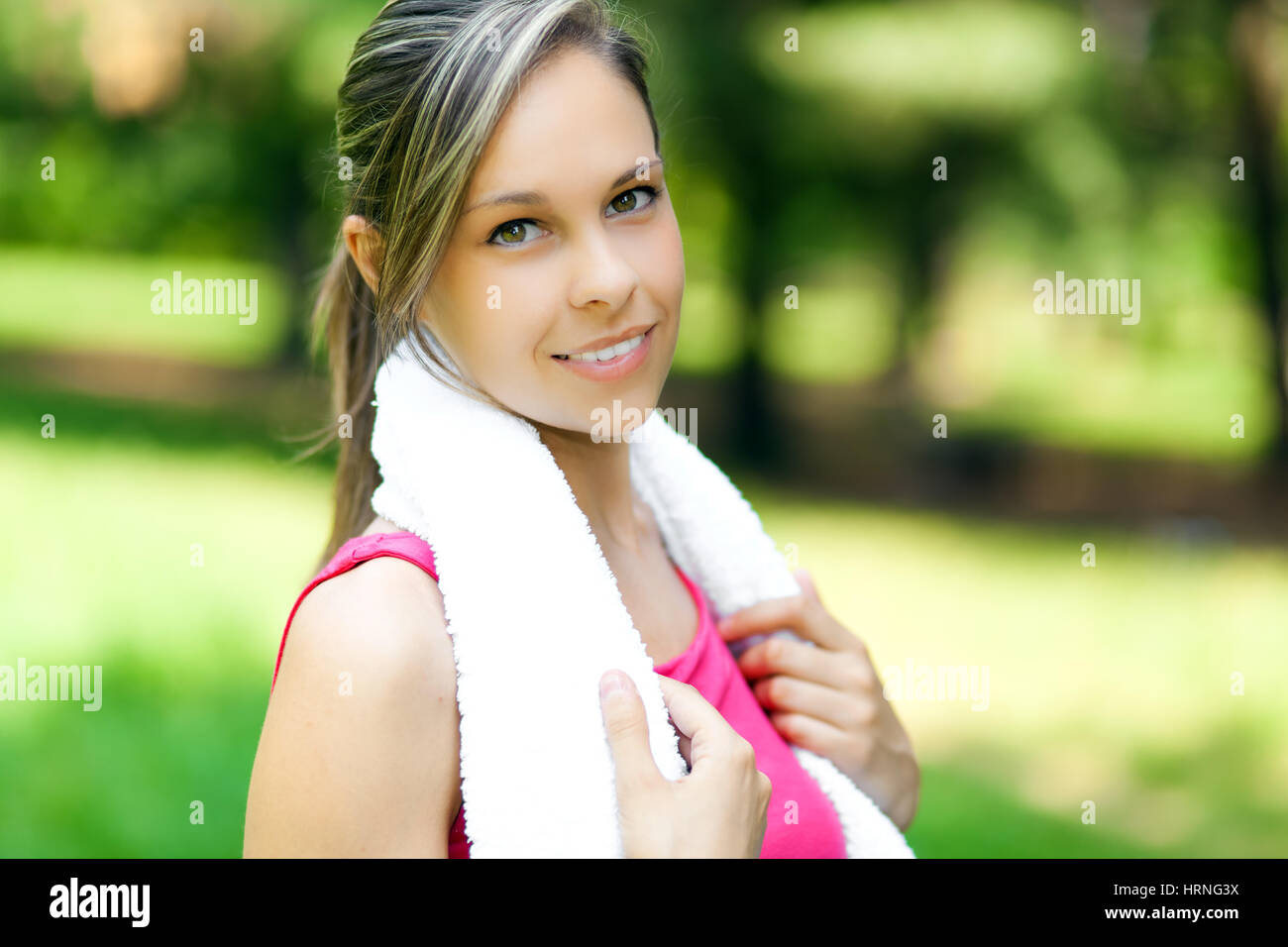 Un attraente femminile stretching prima del suo allenamento nel parco Foto Stock