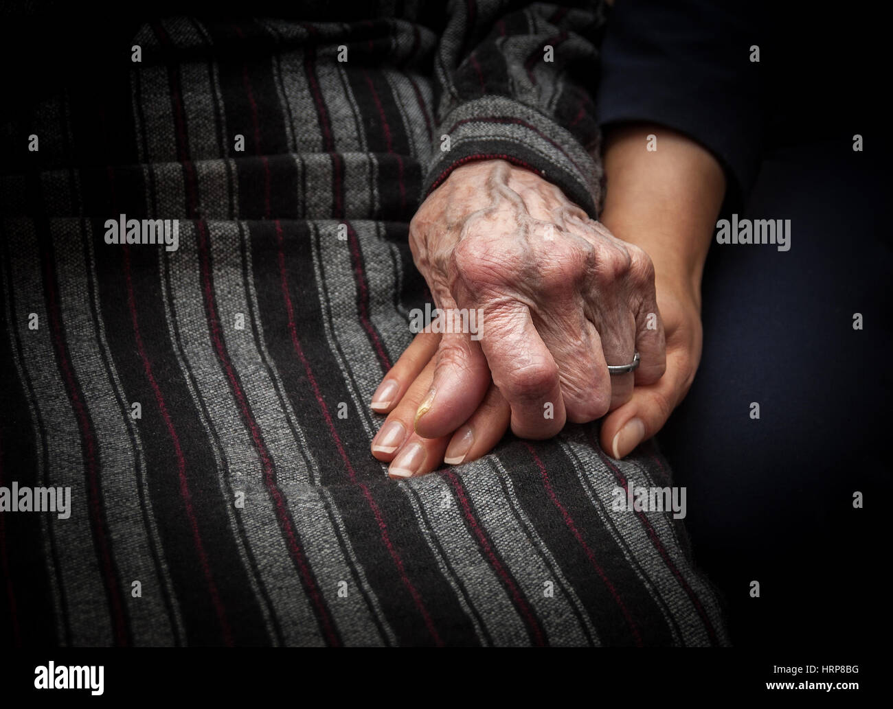 Pelle rugosa mano della donna di età tenendo la mano della giovane donna Foto Stock