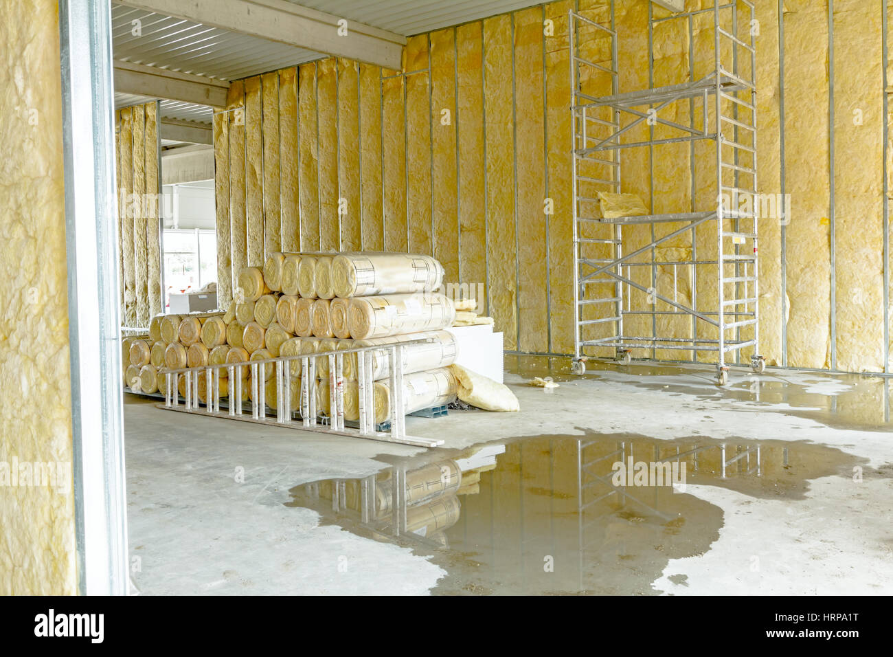 Pila di isolamento termico del materiale in rotolo è avvolta con foglio di cellophane. Usato ponteggio mobile per completare la parete divisoria Foto Stock