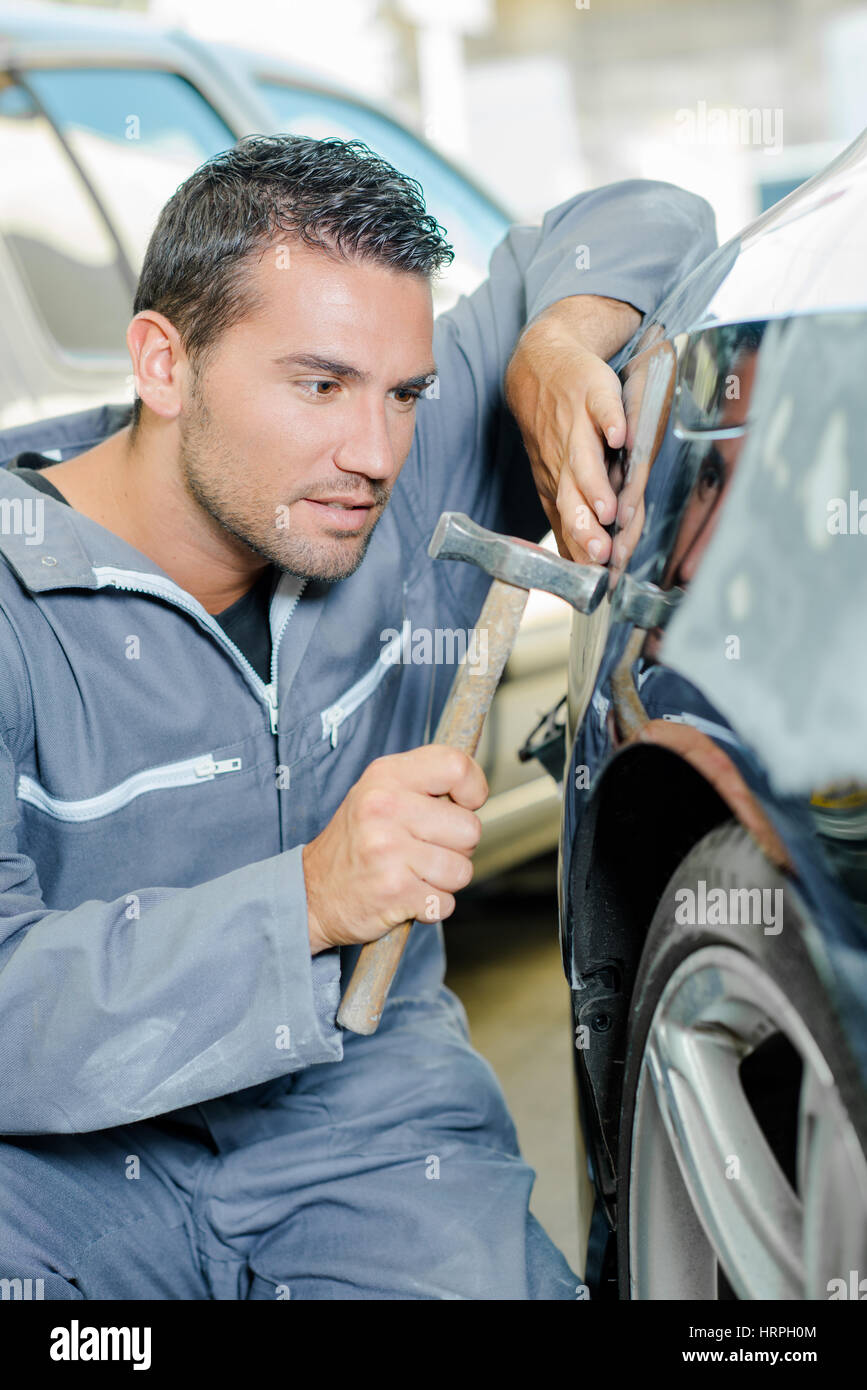 L'uomo con il martello toccando auto Foto Stock