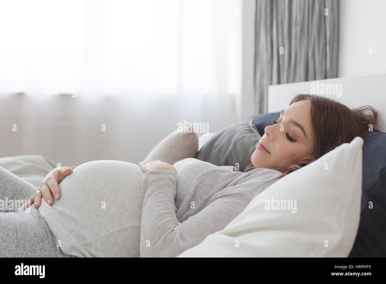 Femmine gravide di sdraiarsi su un letto e toccando il suo ventre. Foto Stock
